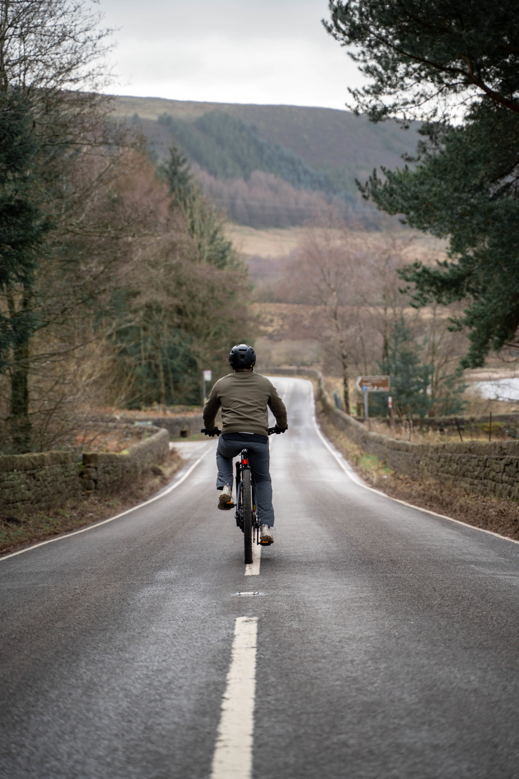 electric mountain bike riding down a long woodland road