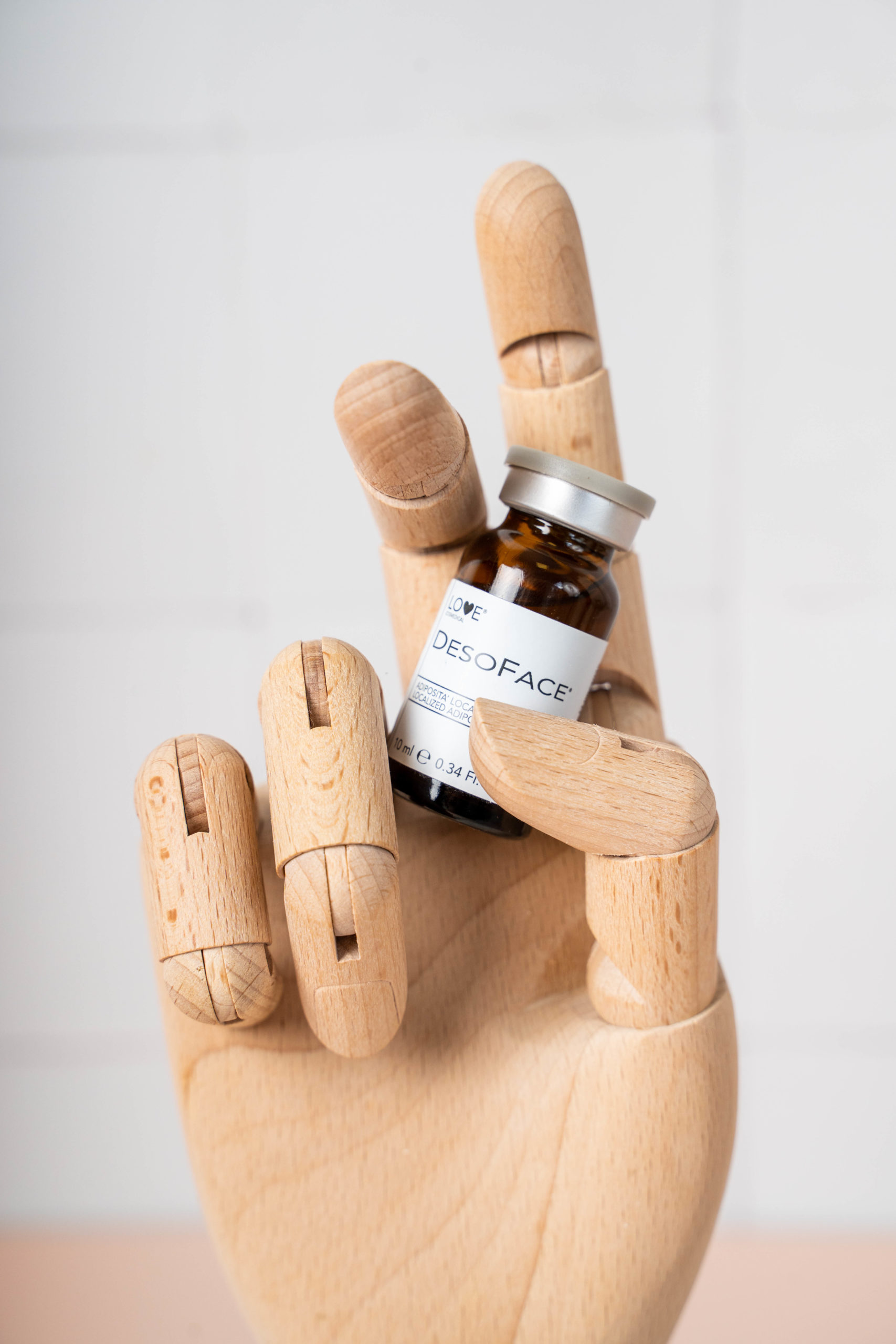 wooden hand holding up an aesthetics product