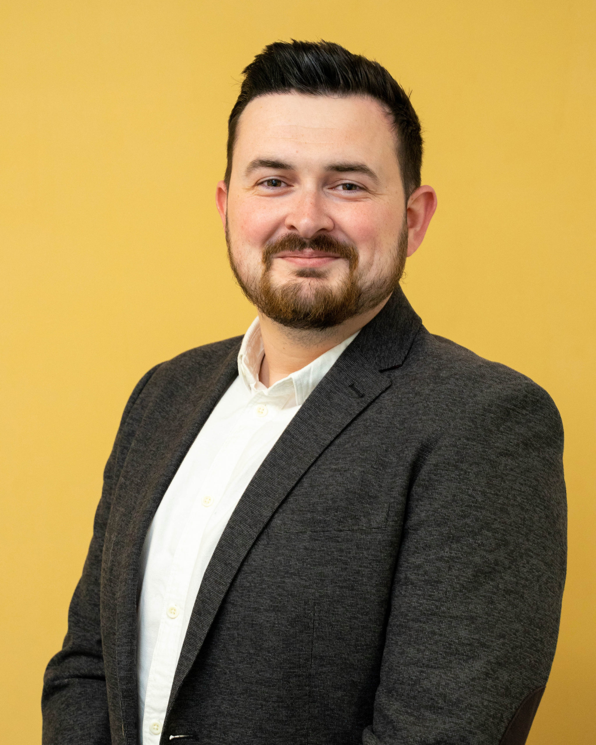 man posing for a headshot against a yellow background